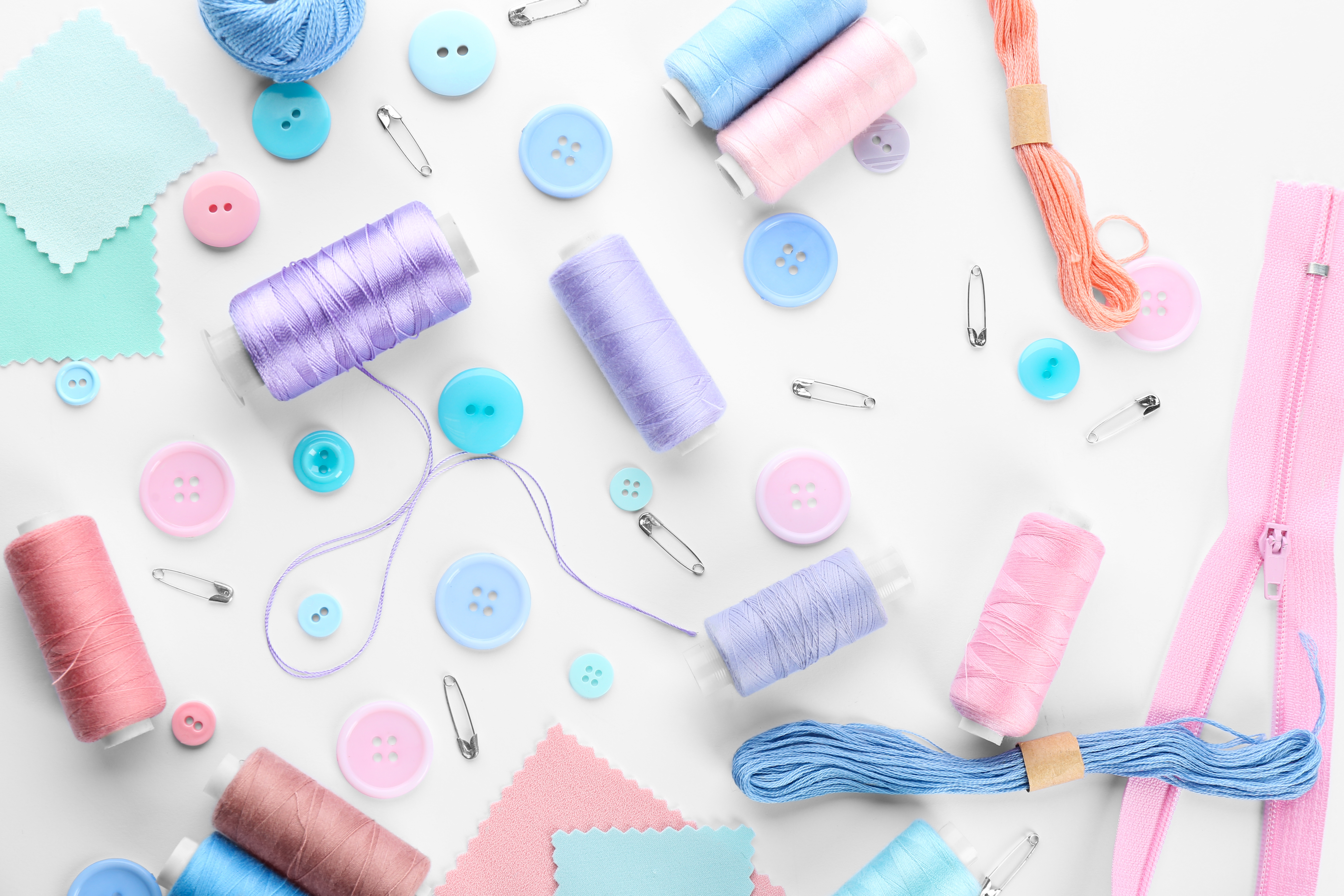 White background with pink, blue, and purple sewing items
