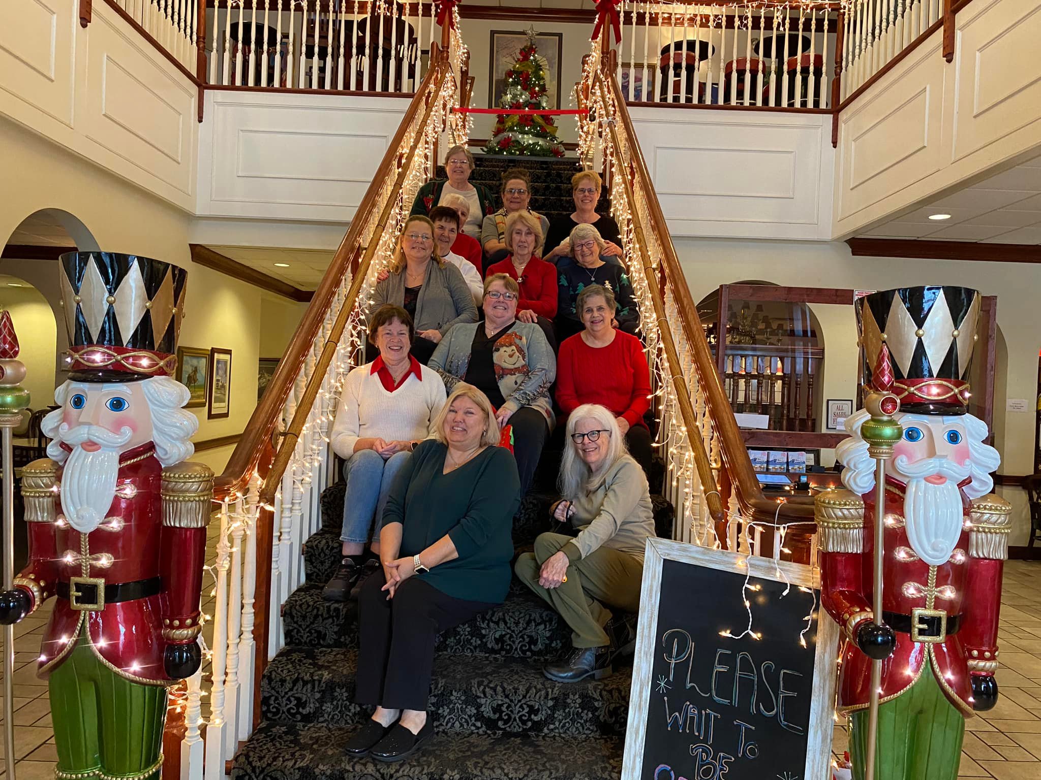 A picture of the loyal homemakers sitting on a staircase decorated for Christmas.