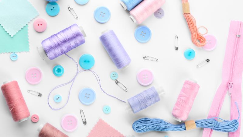 White background with pink, blue, and purple sewing items